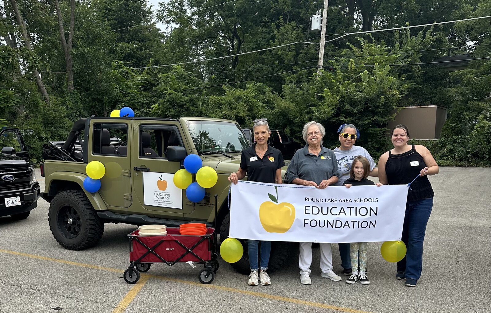 Volunteers with the Foundation banner and decorated Jeep at the Homecoming parade